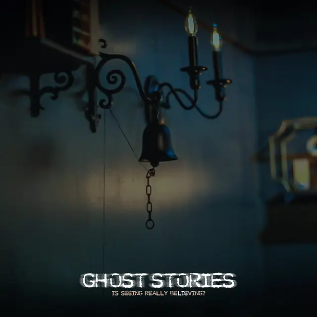 An iron bell hanging from a candle sconce on a dark blue wall