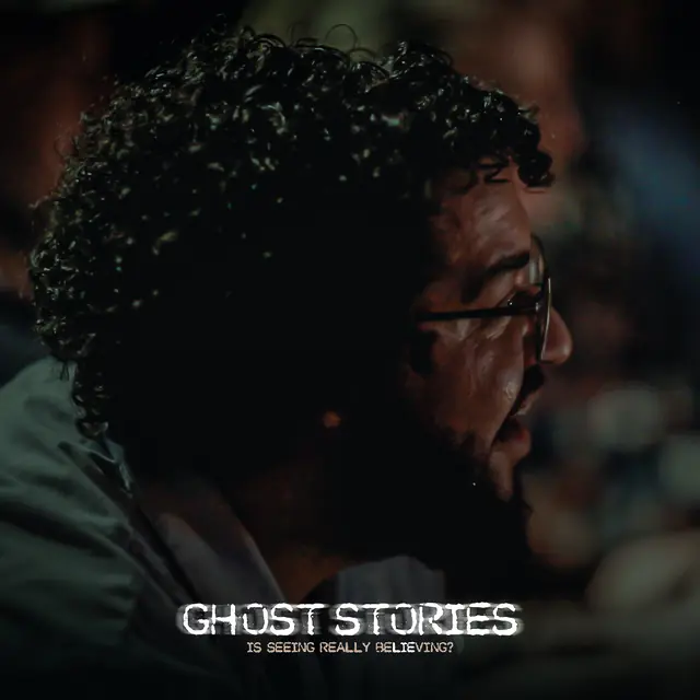 A guest with curly hair and glasses watching intently