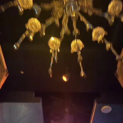A gold chandelier glowing in the dark bar