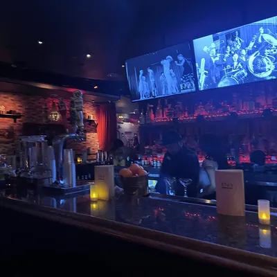 The bar lit in blue with vintage films on the screens