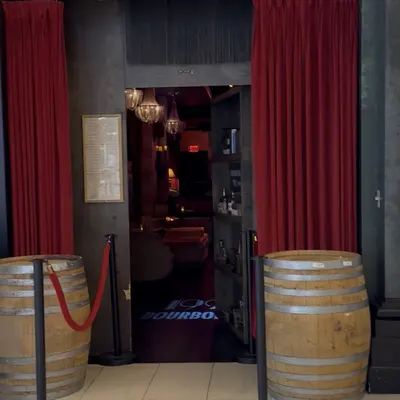 The curtained entrance to 1923 Prohibition Bar, flanked by whiskey barrels